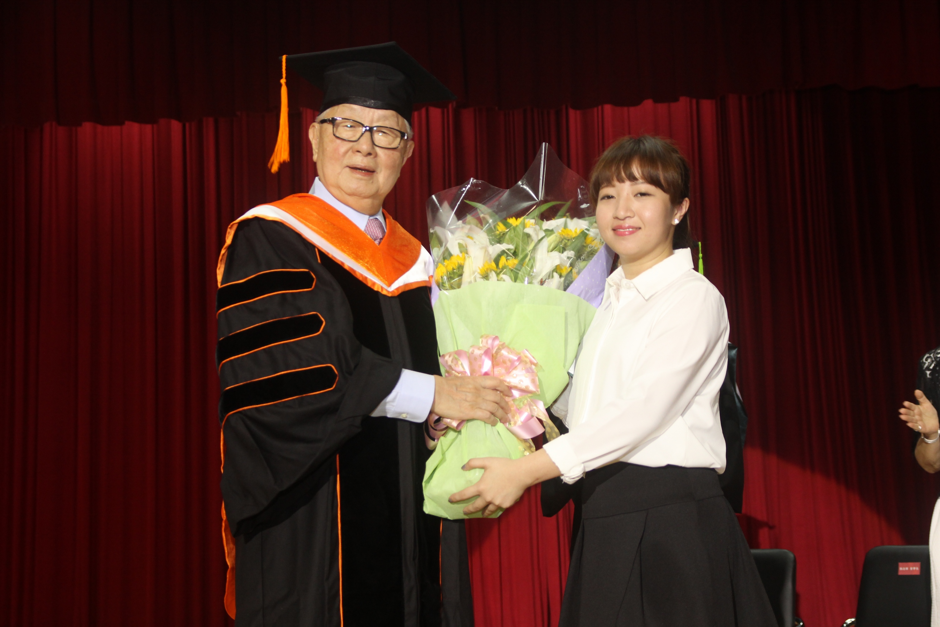 台積電董事長張忠謀接受亞洲大學畢業生代表獻花。